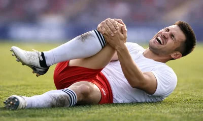 Giocatore infortunato a terra che si tiene il ginocchio